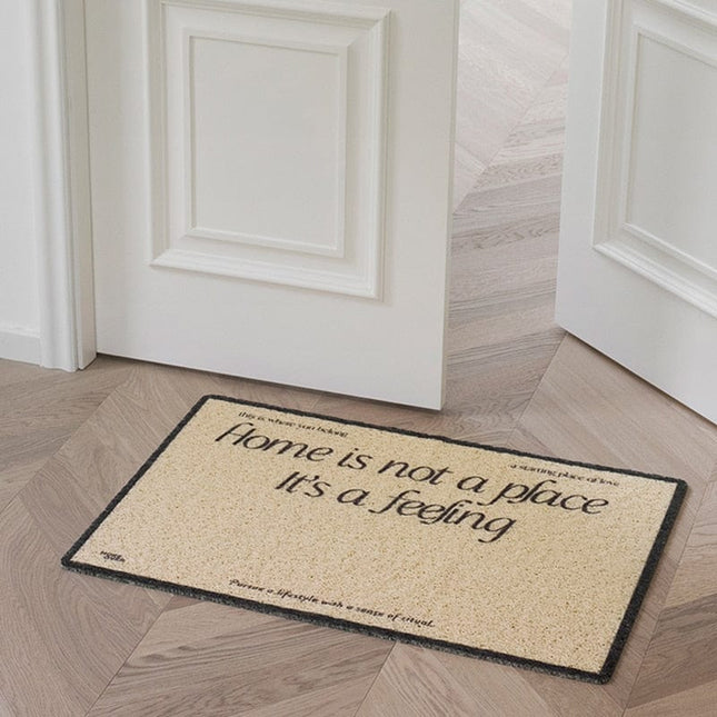 Ovimatto tekstillä "Home is a feeling"